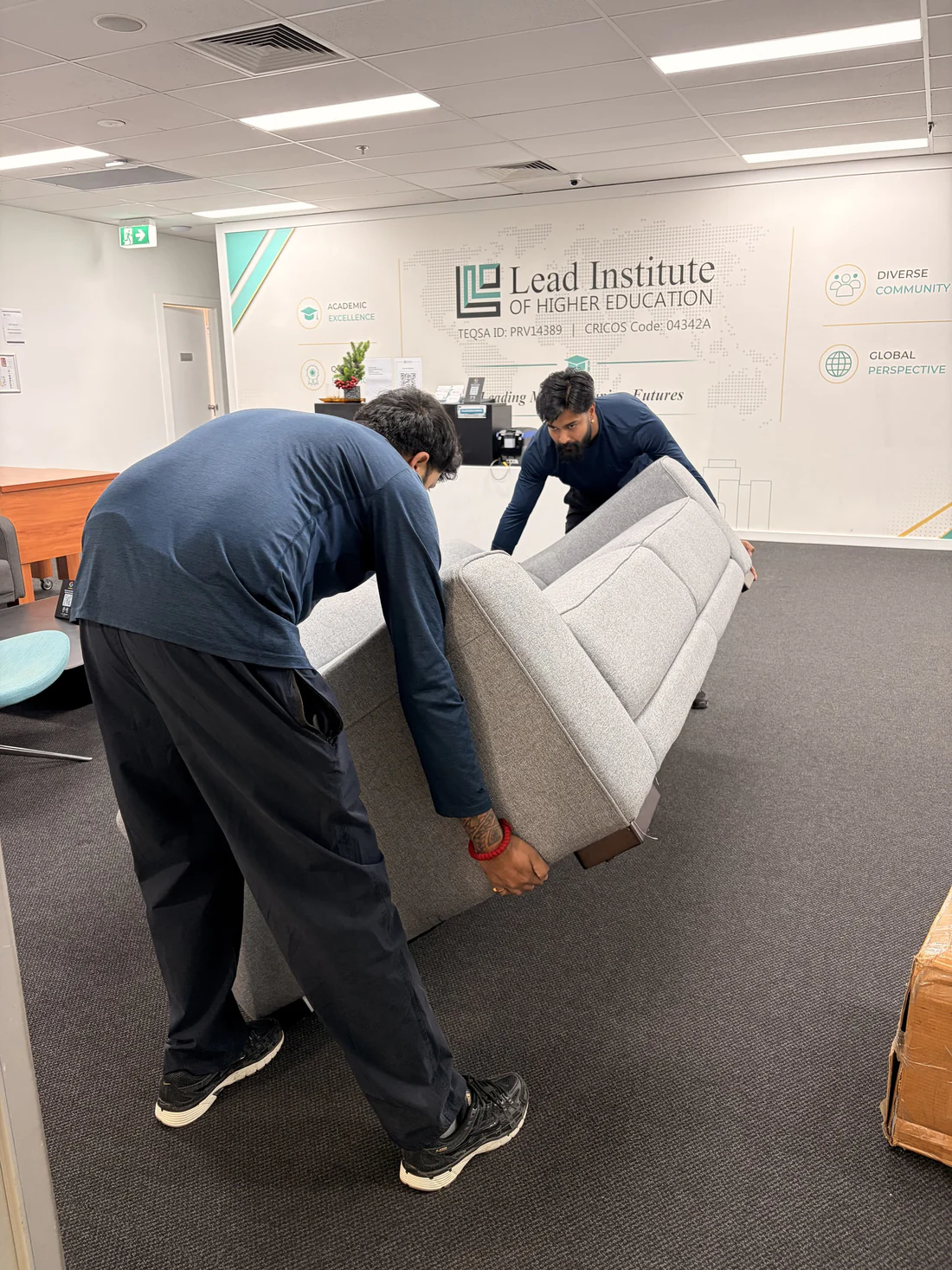 Two of the crew carrying a lounge into an office reception